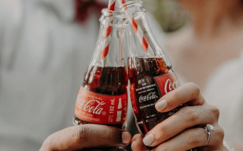 Close-up photo of two hands holding Coca-Cola bottles