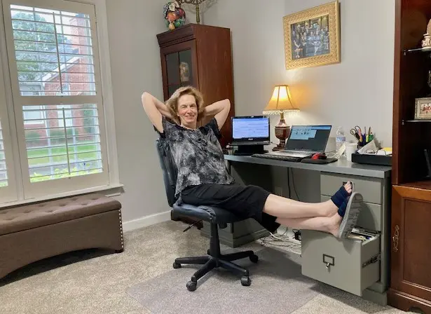 Woman sitting at her office desk with her legs on an open drawer