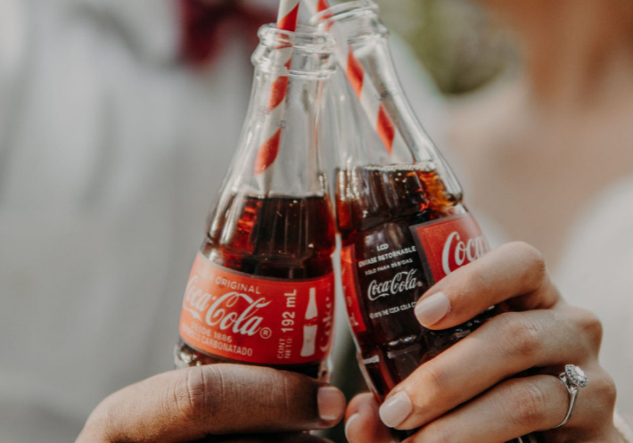 Close-up photo of two hands holding Coca-Cola bottles